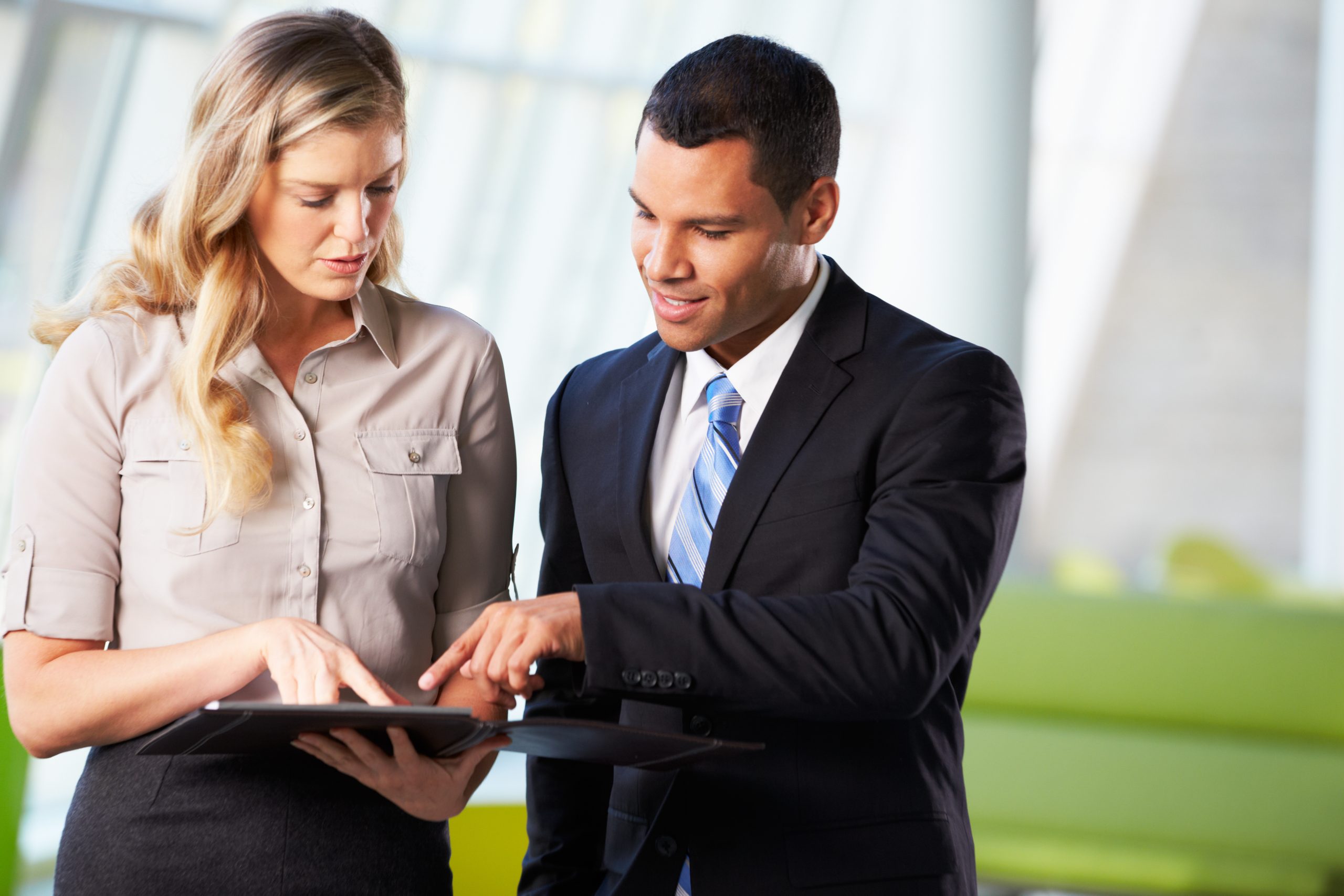 A woman looks at a tablet and a man next to her points to the same tablet