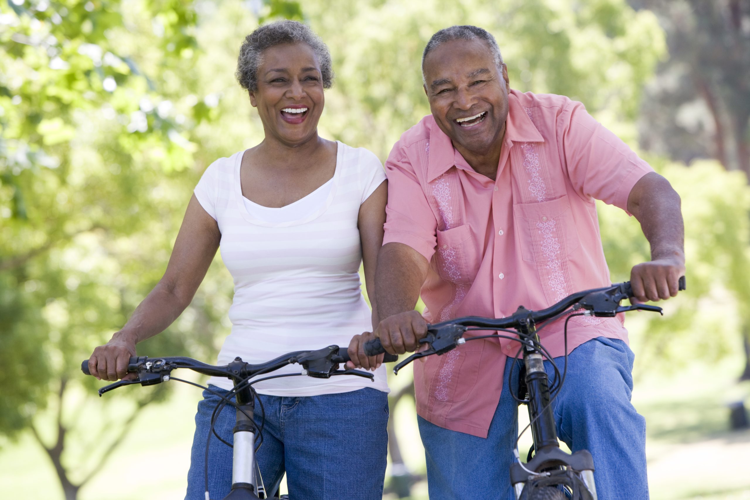 Older couple on bicycles together are posing for the camera